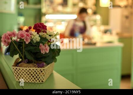 cesto con fiori e blur donna che lavora in pasticceria. negozio di dolci Foto Stock