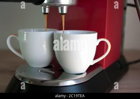 Due tazze di espresso, preparazione del caffè, macchina per caffè rosso. Foto Stock