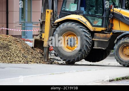 I forti piedini stabilizzatori del trattore si estendono per stabilizzarsi e stabilizzarsi durante lo scavo del terreno durante l'eliminazione dell'acqua Foto Stock