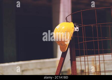 Visualizza casco giallo Safety Engineer con recinzione in metallo e sfondo della costruzione Foto Stock
