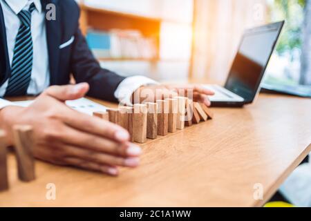 Uomo d'affari proteggere blocco di legno cadere a pianificazione e strategia in rischio di business alternativa e prevenire. Foto Stock