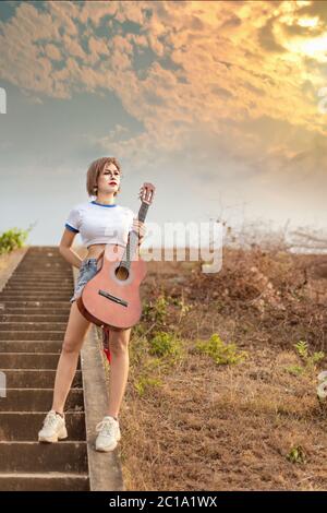 ritratto di donna asiatica con chitarra in natura Foto Stock