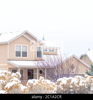 Cornice quadrata Casa innevata e fogliame ghiacciato su un paesaggio panoramico di quartiere in inverno Foto Stock