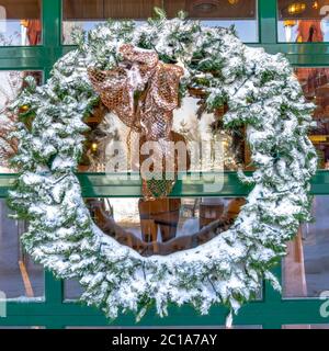 Raccolto quadrato la corona verde innevata appesa alla parete di vetro di un edificio in Wasatch Mountains Foto Stock