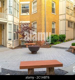Panchine di pietra quadrata intorno al camino fuori di un complesso residenziale Foto Stock