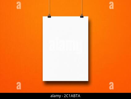 Poster bianco appeso su una parete arancione con clip. Modello di mockup vuoto Foto Stock