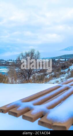 Terreno collinare in verticale innevato vicino al lago ghiacciato Utah in inverno con panca all'aperto vuota Foto Stock