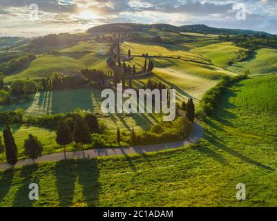 Incredibile tramonto colorato in Toscana. Pittoresco agriturismo e tipica strada curva con cipresso, paesaggio in Toscana, Italia, Europa Foto Stock