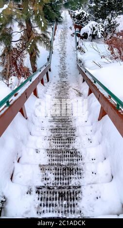 Scala verticale in metallo con grata su pendio in collina ricoperta di neve durante l'inverno Foto Stock