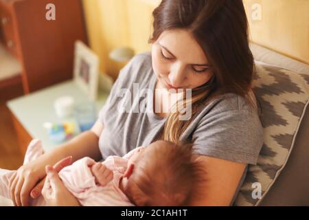 Giovane madre tenendo il suo bambino neonato. Mom lattante. La famiglia a casa Foto Stock