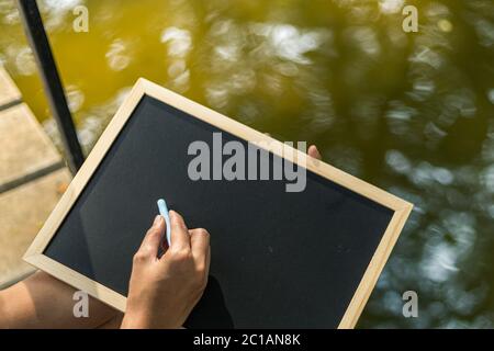 Le mani usano il gesso per disegnare, scrivere la lavagna nei parchi. Istruzione, apprendimento. Foto Stock