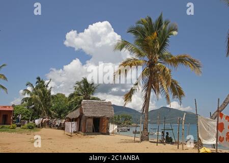 Tovaglie in vendita in vendita in spiaggia con barche, Villaggio Ampangorinana, Isola Nosy Komba, Madagascar. Foto Stock