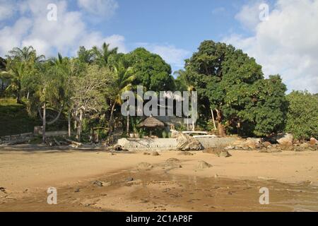 Vista di lapa con tetto di foglie di palma e gli alberi su 293 su Komba Guest House dalla spiaggia, Ampangorinana Village, Isola di Nosy Komba, Madagascar. Foto Stock