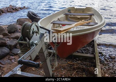 Una barca a remi rossa (barca a remi) su uno scivolo con un verricello sulla riva del lago in Finlandia Foto Stock