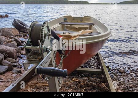 Una barca a remi rossa (barca a remi) su uno scivolo con un verricello sulla riva del lago in Finlandia Foto Stock