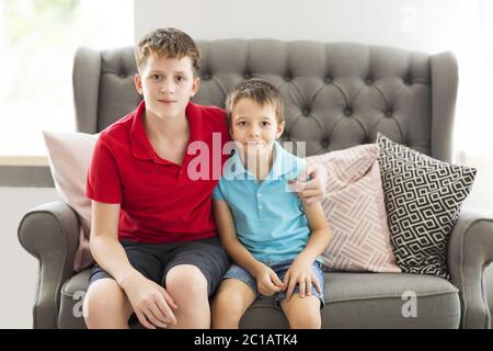 Fratello maggiore sul divano abbracciando fratello minore Foto Stock