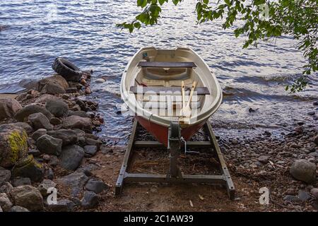 Una barca a remi rossa (barca a remi) su uno scivolo con un verricello sulla riva del lago in Finlandia Foto Stock