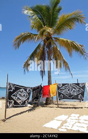 Tovaglie in vendita in vendita in spiaggia con palme, Villaggio Ampangorinana, Isola Nosy Komba, Madagascar. Foto Stock