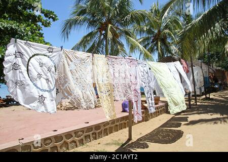 Tovaglie in vendita sospese in vendita sul marciapiede, Villaggio Ampangorinana, Isola Nosy Komba, Madagascar. Foto Stock