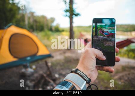 uomo che prende la foto del telefono delle donne che posano sull'amaca Foto Stock