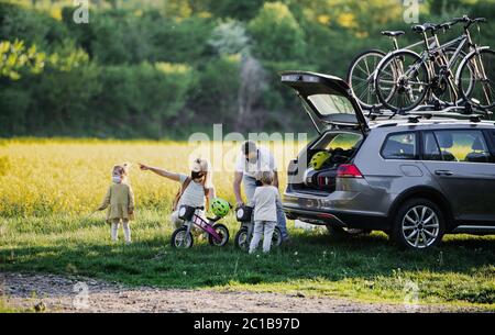 Famiglia con due bambini piccoli e maschere di protezione in viaggio in bicicletta in campagna. Foto Stock