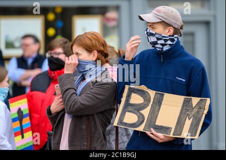 Richmond, North Yorkshire, UK - 14 giugno 2020: Due manifestanti BLM regolano i rivestimenti protettivi mentre tengono un cartello fatto in casa a Black Live Foto Stock