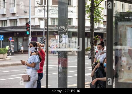 BELGRADO, SERBIA - 9 MAGGIO 2020: Ragazze che indossano una maschera respiratoria in attesa di trasporto in una fermata dell'autobus di Belgrado, durante il coronaviru Foto Stock