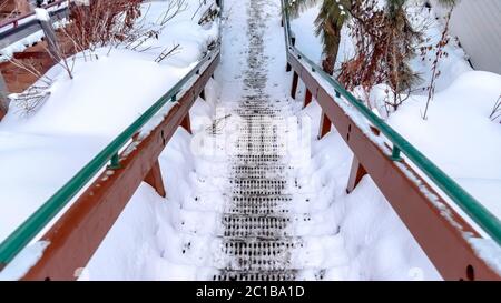 Panorama Crop grate scala in metallo battistrada su pendio collina ricoperta di neve durante l'inverno Foto Stock