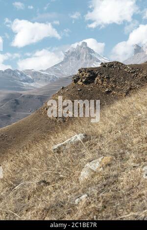 Paesaggio montano autunnale di pendii e erba gialliti in montagna con rocce epiche e parti di piste innevate su una su Foto Stock