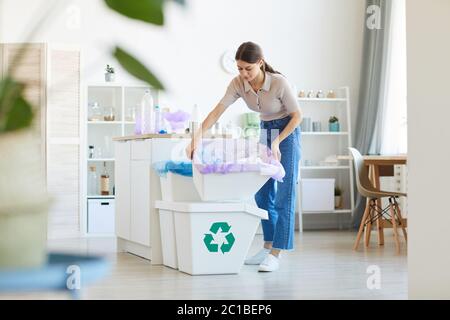 Giovane donna che getta fuori la spazzatura che porta i bidoni in cucina Foto Stock