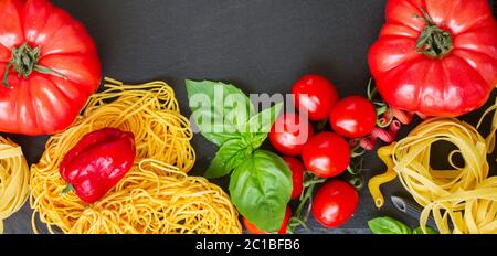 La pasta grezza con ingridients sulla lavagna nera Foto Stock