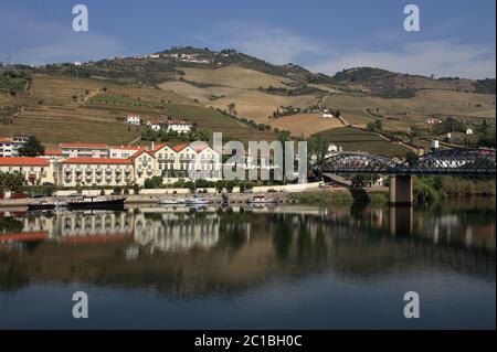 Portogallo, Regione del Douro, Pinhao. Vista panoramica di Pinhao e del suo ponte in acciaio sul fiume Douro che si riflette sull'acqua. Sito patrimonio dell'umanità dell'UNESCO. Foto Stock