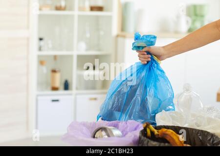 Primo piano di donna che getta borsa con spazzatura nel cestino della spazzatura mentre facendo lavoro domestico a casa Foto Stock