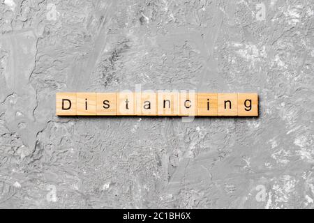 parola di distanza scritta su blocco di legno. testo di distanza su tabella di cemento per il vostro desing, concetto. Foto Stock