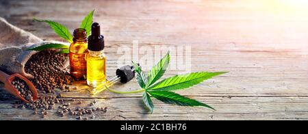 Foglie di bottiglie d'olio Marijuana e Cannabis e semi interi in legno Foto Stock