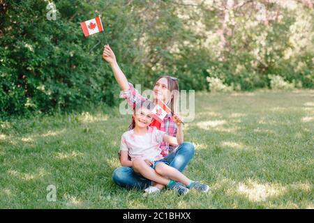 Mamma di famiglia con figlio che festeggia la festa nazionale del Canada il 1 luglio. Madre caucasica con bambino che sventolava bandiere canadesi. I cittadini fieri festeggiano Foto Stock