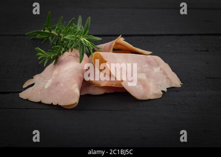 Carne fredda fette di prosciutto su rustiche tavoli in legno nero con spazio per il testo in background o in primo piano Foto Stock