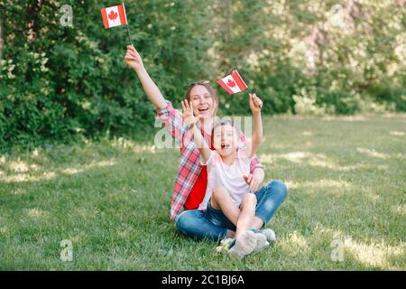 Mamma di famiglia con figlio che festeggia la festa nazionale del Canada il 1 luglio. Madre caucasica con bambino che sventolava bandiere canadesi. I cittadini fieri festeggiano Foto Stock