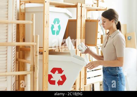 Giovane donna che smista i rifiuti nei contenitori in plastica del magazzino Foto Stock