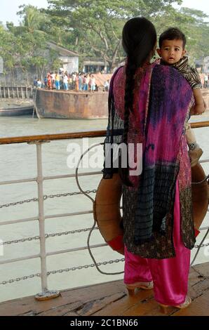 Una madre e un bambino che si levano sul ponte del piroscafo a pale Rocket quando la nave arriva a un piccolo molo. Corsi d'acqua del delta del Gange in Bangladesh. Foto Stock