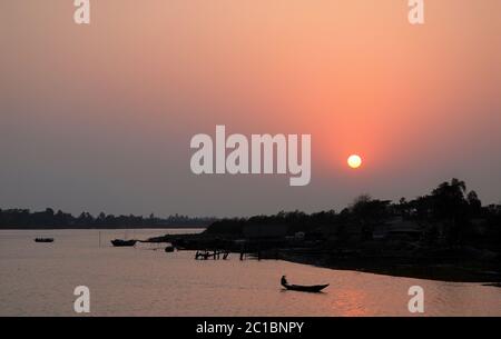 Tramonto sul delta del Gange in Bangladesh. Una piccola barca che si addormeggia sul fiume e si staglia in una luce rosa. Persona non identificabile. Foto Stock