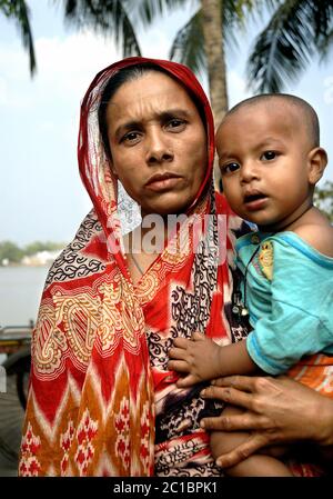 Khulna in Bangladesh. Donna in abiti tradizionali che tiene un bambino. Vita locale a Khulna. Foto Stock