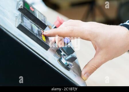 un primo piano dell'operatore l'uomo preme il pulsante sul pannello di controllo con i dispositivi di controllo sulla produzione di mobili. Foto Stock