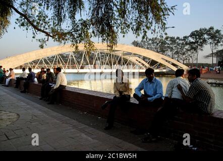 Dhaka in Bangladesh. Jatiya Sangsad Bhaban, la Casa del Parlamento Nazionale del Bangladesh. Persone che siedono presso un lago nel terreno dell'edificio. Foto Stock