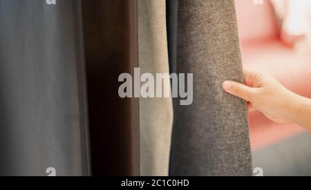 Mano femminile scelta foglio di tessuto o tessuto. Gruppo di orologi multicolore in tessuto tonalità terra per il materiale di finitura di lenzuola o mobili. Casa Foto Stock