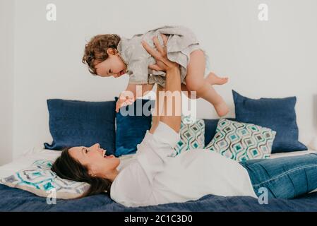la giovane bella madre gioca con la figlia a letto a casa Foto Stock