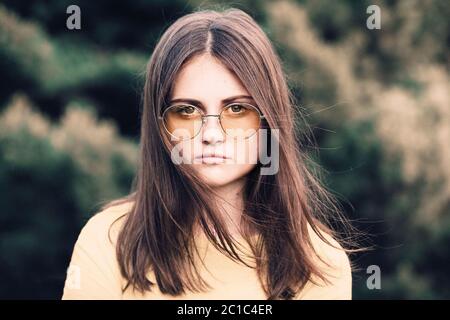 Ritratto di una ragazza adolescente con capelli lunghi in un bicchiere giallo Foto Stock