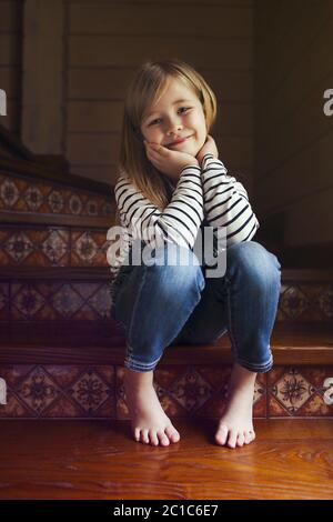 Felice bambina carina seduta sulle scale Foto Stock