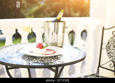 Bottiglia di champagne con bicchieri e dessert sul tavolo Foto Stock