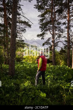 Turista con tazza di caffè nella foresta lussureggiante in montagna all'aperto Foto Stock